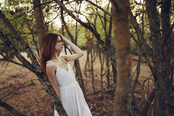 istock pretty woman leaning on tree trunk outdoors in garden cropped view 2104657916