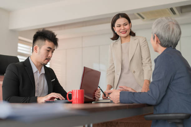 istock Leadership Dialogue: Asian Female Executive and Male Advisor in Modern Office Scene 2104681554