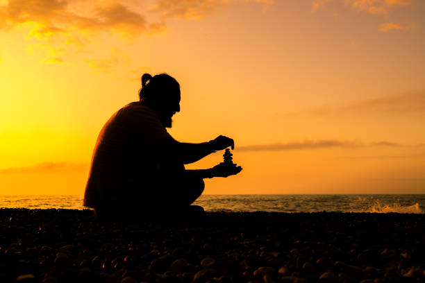 istock A man is sitting on the beach, holding stones collected on the beach 2104683705