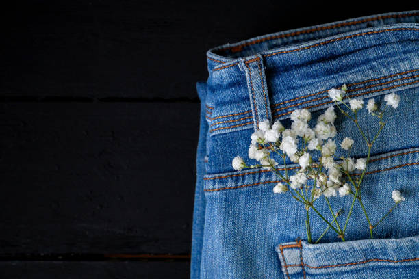 Flowers in jeans pocket on black background
