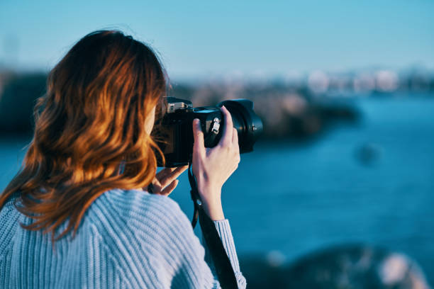 istock woman with camera on nature sea landscape 2104712577