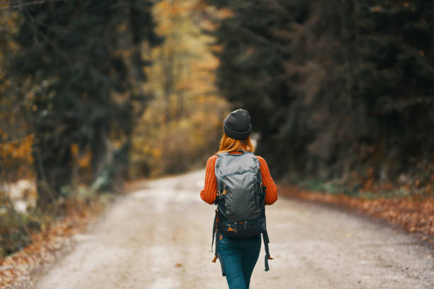 istock Traveler with a backpack in the forest on the road in autumn trees model 2104748889