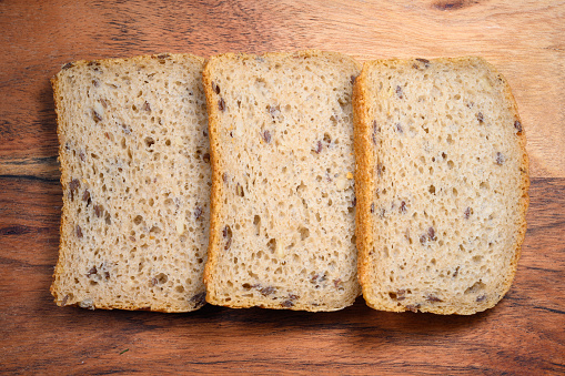 Sliced rye bread on wooden board, top view, close-up