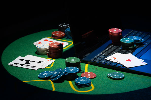 Scattered poker chips and cards on a green table with and laptop stock photo