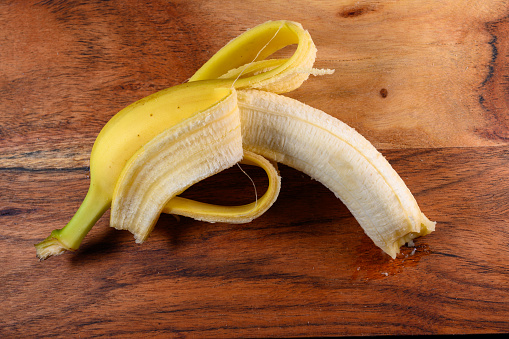 Pelled banana on wooden board close-up