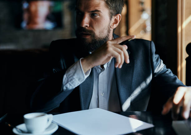 istock business man sitting at a table in a cafe documents work official coffee cup 2104835468
