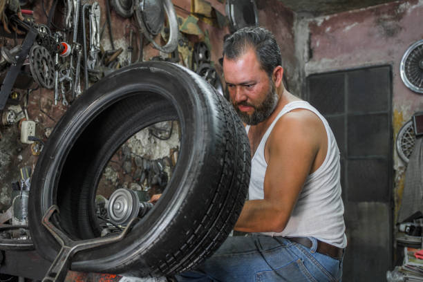 tireman brushes a flat tire to patch it with a power tool in his garage. local business concept
