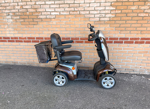 Modern mobility scooter parked against brick building