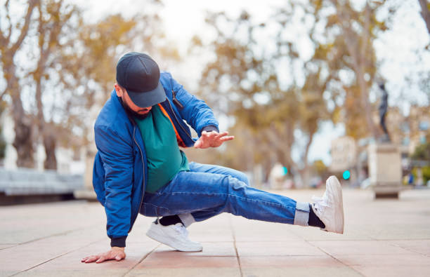 istock breakdancer guy performing downrock or floor based footwork stunt on the street 2104852359