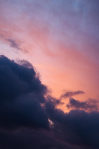 Vertical photograph of pink, blue clouds in overcast weather at sunset. Romantic sky. Aesthetically pleasing neutral photo.