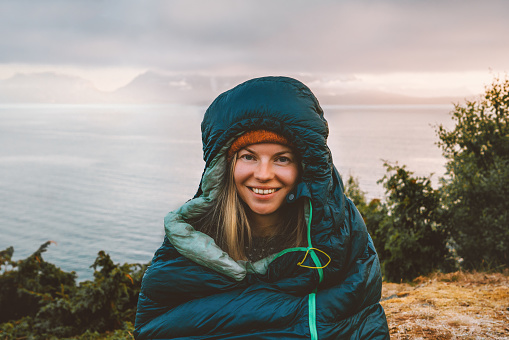Woman hiker in sleeping bag camping gear morning in mountains active travel vacations outdoor, traveler girl portrait in Norway active adventure eco tourism healthy lifestyle hobby