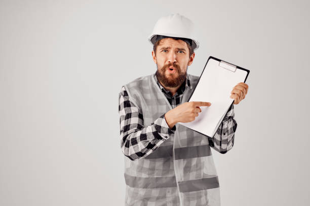 istock male builder in a white helmet blueprints Professional light background 2104878055