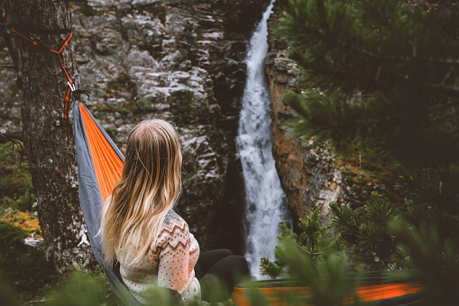 Woman traveling outdoor camping  vacations girl in hammock enjoying waterfall view hiking solo active tourist exploring northern Norway adventure healthy lifestyle trip sustainable tourism weekend