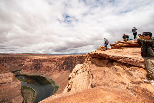 Horseshoe Bend, Page Arizona - a group of tourists atop a cliff unprotected