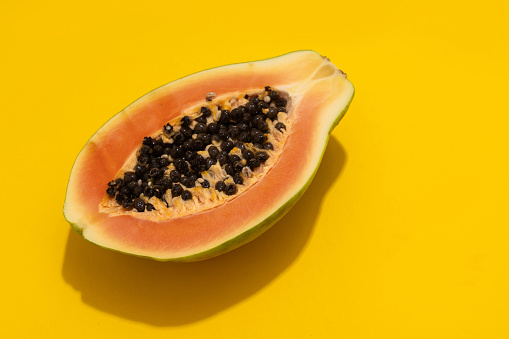 Ripe papaya, sliced into two pieces on the black aged table surface.