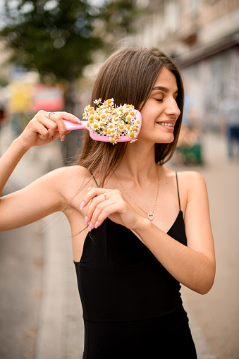 Engrossed in a floral embrace, a girl meticulously combs her hair, each stroke intertwining with vibrant blooms, creating a mesmerizing fusion of nature's charm with personal grooming.