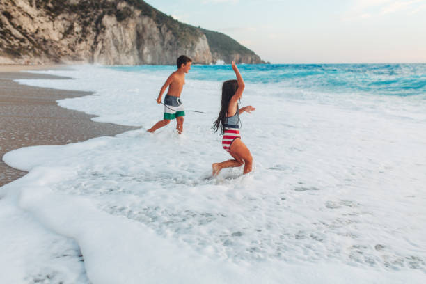 istock Brave children splashing with waves on a beautiful beach 2105025851