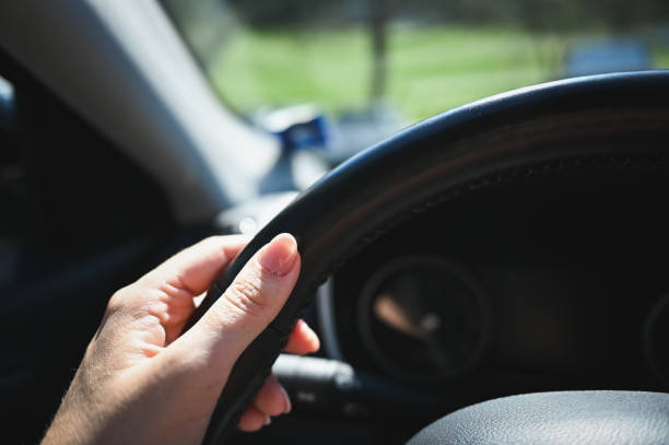istock woman's hand holding car steering wheel. 2105030536