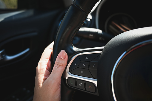 Close up of a woman's hand on steering wheel in car