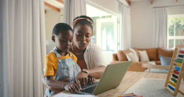 istock Education, laptop and teaching with black family in home for child development, learning or study. Computer, homework and typing with woman helping kid school student in dining room of apartment 2105044631
