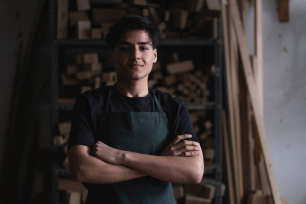istock young carpenter with arms crossed in workshop looking at camera 2105047296