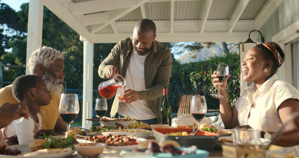 istock Dinner, black family and juice at table on patio for Easter celebration, fun and eating together at home. Grandparents, parents and kids in conversation for food, drinks and love in backyard in USA. 2105059825