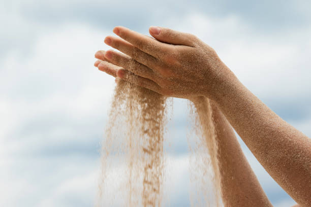 istock Female hands with sand gracefully flowing through the fingers, symbolizing different concepts 2105059840
