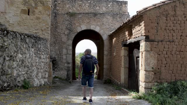 A man walks towards the old entrance of a medieval village in Maderuelo, Spain.