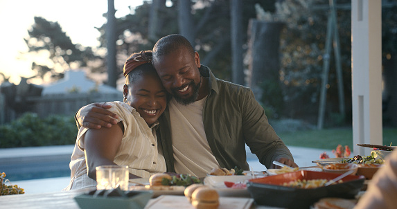 Mature couple, happy and patio for dinner in table with food for bonding, laugh and smile in Atlanta. Home, black people and family with relationship for meal on joy, fun and together with hug.