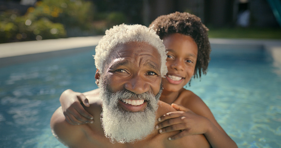 Old man, child and portrait in swimming pool for happy summer bonding on holiday, vacation or traveling. Grandfather, boy and face in backyard garden or piggyback connection, stress relief or family