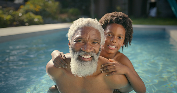 Old man, child and portrait in swimming pool for relax summer bonding on holiday, vacation or traveling. Grandfather, boy and face in backyard garden for piggyback connection, happiness or family