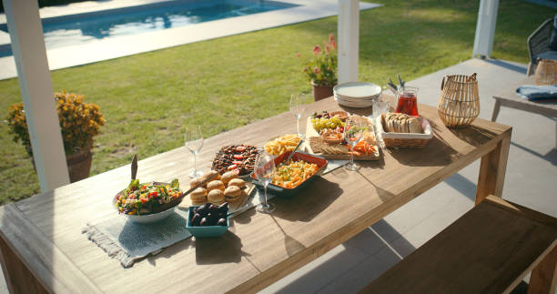 Lunch, food and table on backyard patio for weekend celebration, Easter meal or bbq picnic at pool. Brunch, drinks and setting for outdoor social gathering in garden with home cooking event in sun.