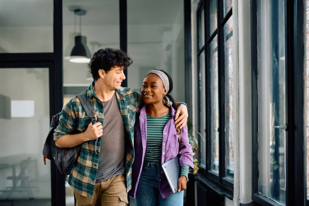 istock Happy student couple walking embraced through the university. 2105092578