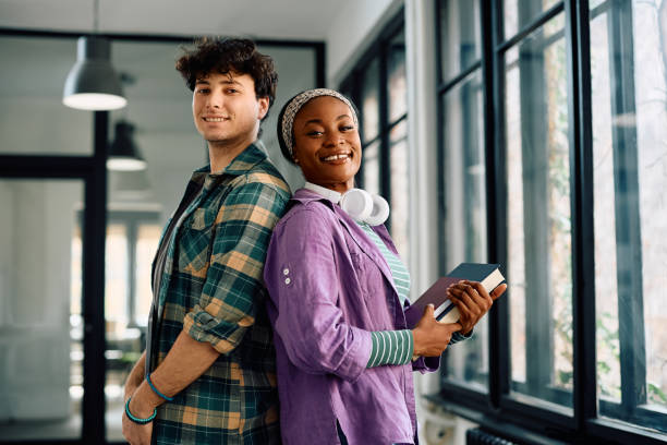 istock Happy student couple at the university looking at camera. 2105095783