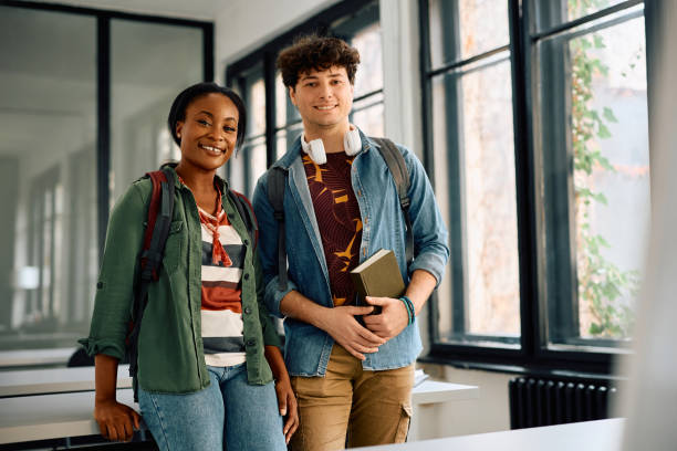 istock Happy multiracial student couple at university classroom looking at camera. 2105097926