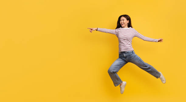 istock Funny young korean lady jumping in air, pointing copy space 2105098479