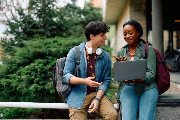happy university students e-learning while using laptop at campus. - öğrenci stok fotoğraflar ve resimler
