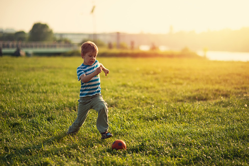 Portrait of a funny little boy playing soccer at the evening near a river. The boy is making a wonderfully funny face.
Shot with Nikon D800