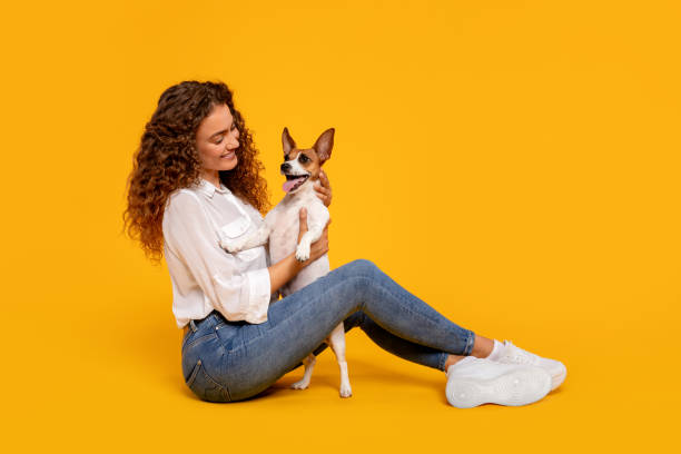 istock Curly-haired woman adoring her dog on yellow background 2105121257