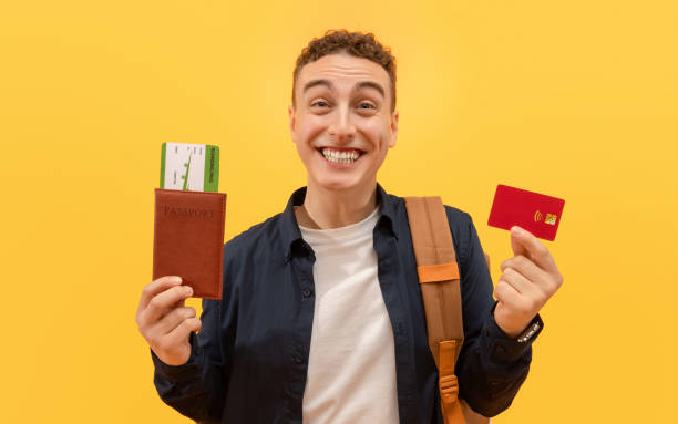 istock Emotional young guy showing tickets and credit card 2105132770