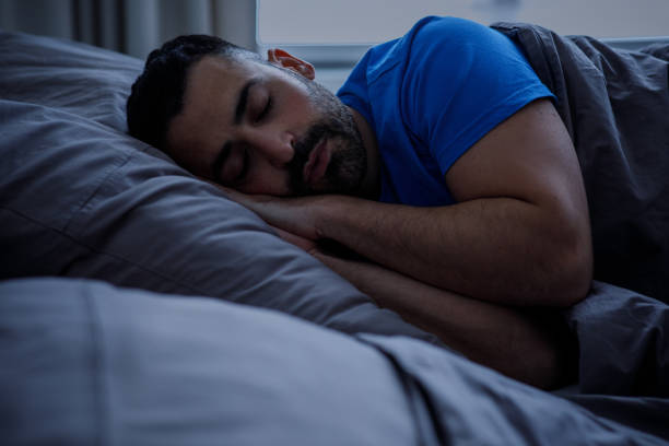 istock Sleep, insomnia and people, conceptually speechless man lying in bed at home at night 2105142369