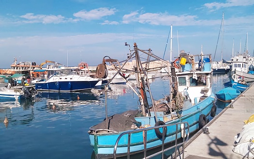 Fisherman putting the fishing net into the water. He is standing on his boat. Sun in back.