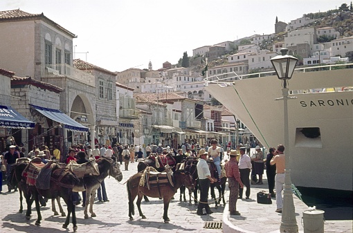 Greece (unfortunately the exact location is not known), 1974. Harbor scene with tourists, locals, buildings and a ferry on a Greek Aegean island.