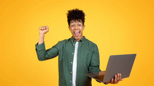 istock Emotional black guy with laptop in his hand gesturing 2105198802