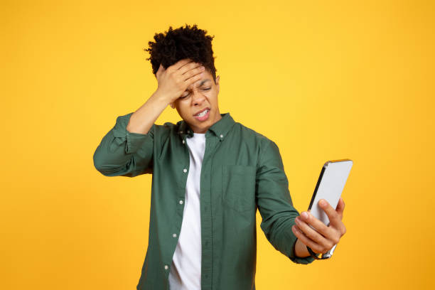 istock Angry black guy looking at smartphone screen, touching head 2105199386