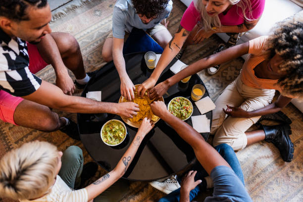 Young friends eating guacamole with nacho at home