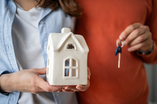 A couple in love holds the keys to their new apartment with eyes filled with happiness and joy. Their smiles reflect excitement and a sense of accomplishment as they retrace their steps toward their shared home.