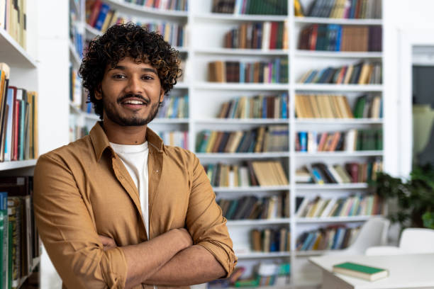 istock Confident young man with arms crossed standing in a library 2105259896