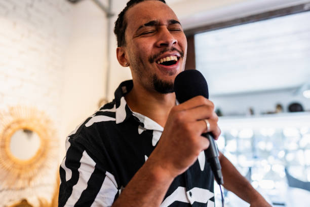 istock Young man singing karaoke at home 2105280931