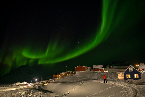 Aurora borealis illuminates skier and homes